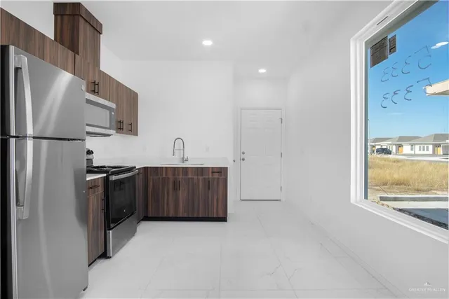 a kitchen with stainless steel appliances granite countertop a refrigerator a stove a sink and dishwasher