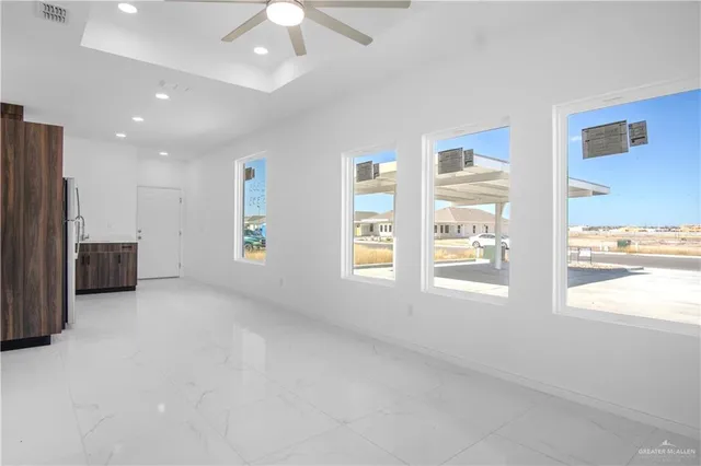 an empty room with windows and fan