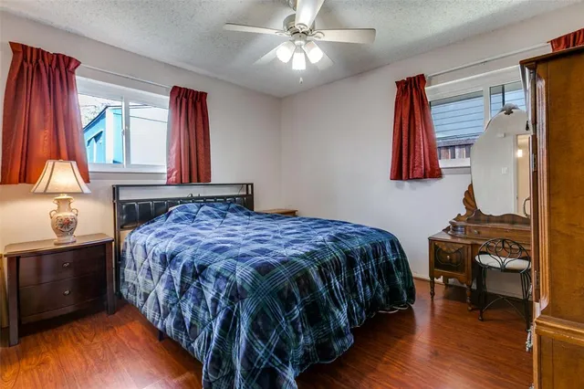 a bedroom with a bed and dresser with wooden floor
