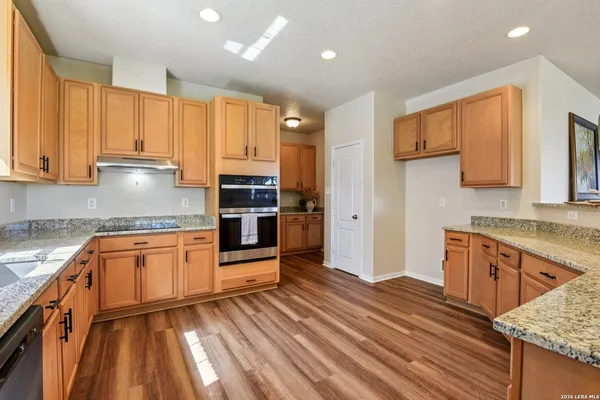 a large kitchen with granite countertop a stove top oven a sink dishwasher a dining table and chairs with wooden floor