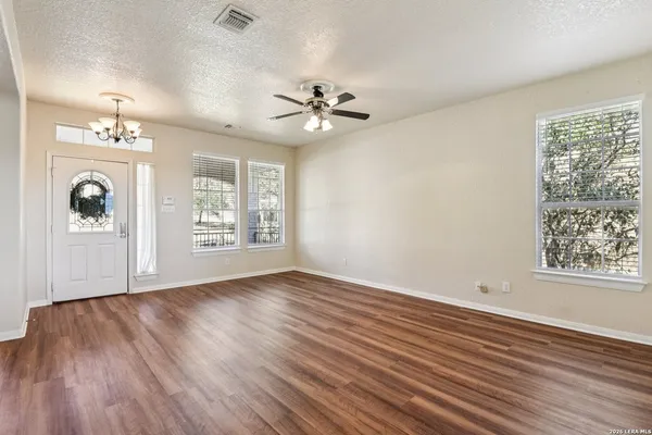 a view of an empty room with wooden floor and a ceiling fan