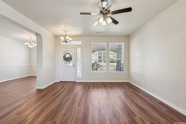 an empty room with wooden floor chandelier and windows
