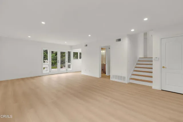 a view of an empty room with wooden floor and stairs