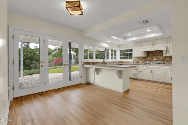 a kitchen with stainless steel appliances granite countertop a stove top oven a sink with wooden floors and white cabinets