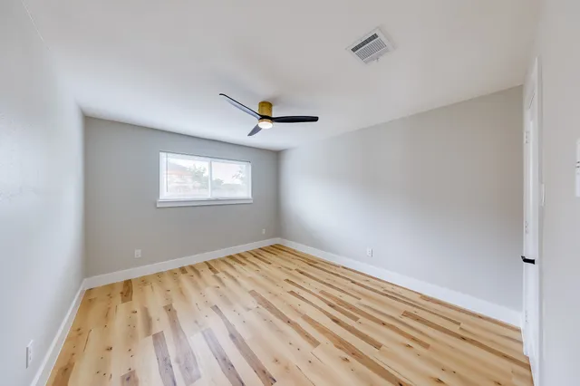 a view of empty room with wooden floor and fan