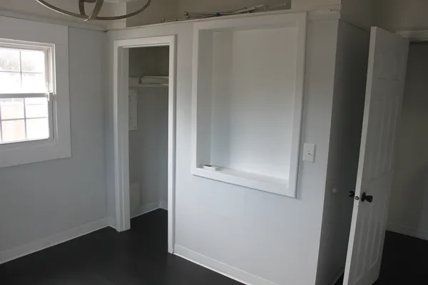an empty room with wooden floor closet and windows