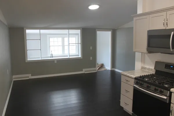 a kitchen with granite countertop a stove and a wooden floor
