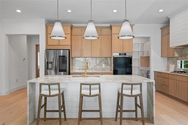 a kitchen with stainless steel appliances granite countertop a kitchen island a stove and a refrigerator