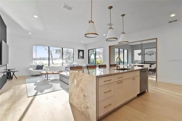 a large kitchen with kitchen island a large counter space a sink a window and chairs
