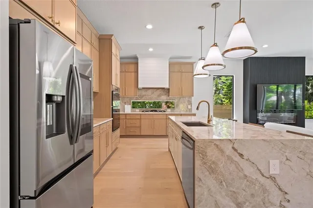 a large kitchen with stainless steel appliances kitchen island granite countertop a refrigerator a oven a sink and a dining table with wooden cabinet