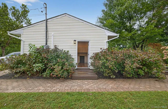 a view of a white house next to a yard with plants and trees