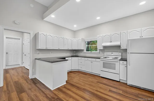 a kitchen with granite countertop white cabinets and white appliances