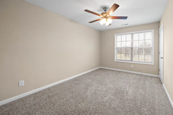 an empty room with a window and a ceiling fan