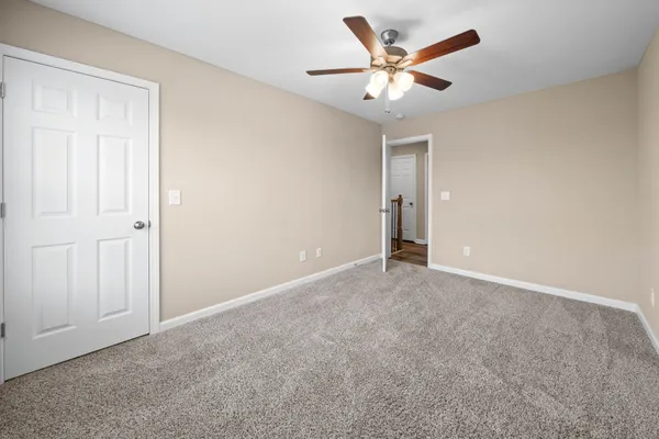 an empty room with closet and a ceiling fan