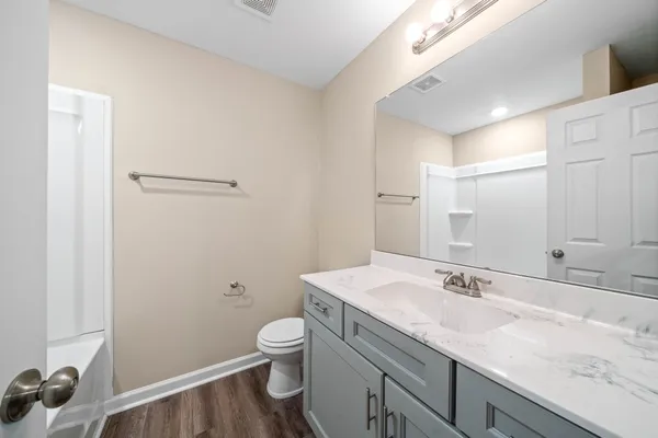 a bathroom with a granite countertop sink a toilet and a mirror