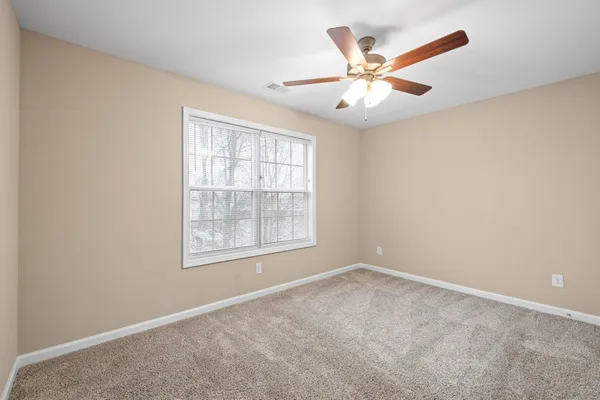 an empty room with window and ceiling fan