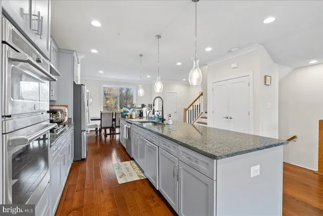 a kitchen with stainless steel appliances granite countertop wooden cabinets a stove a sink and a wooden floors