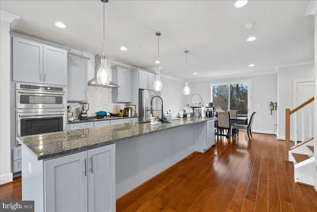 a kitchen with stainless steel appliances granite countertop a sink a stove and a wooden floors