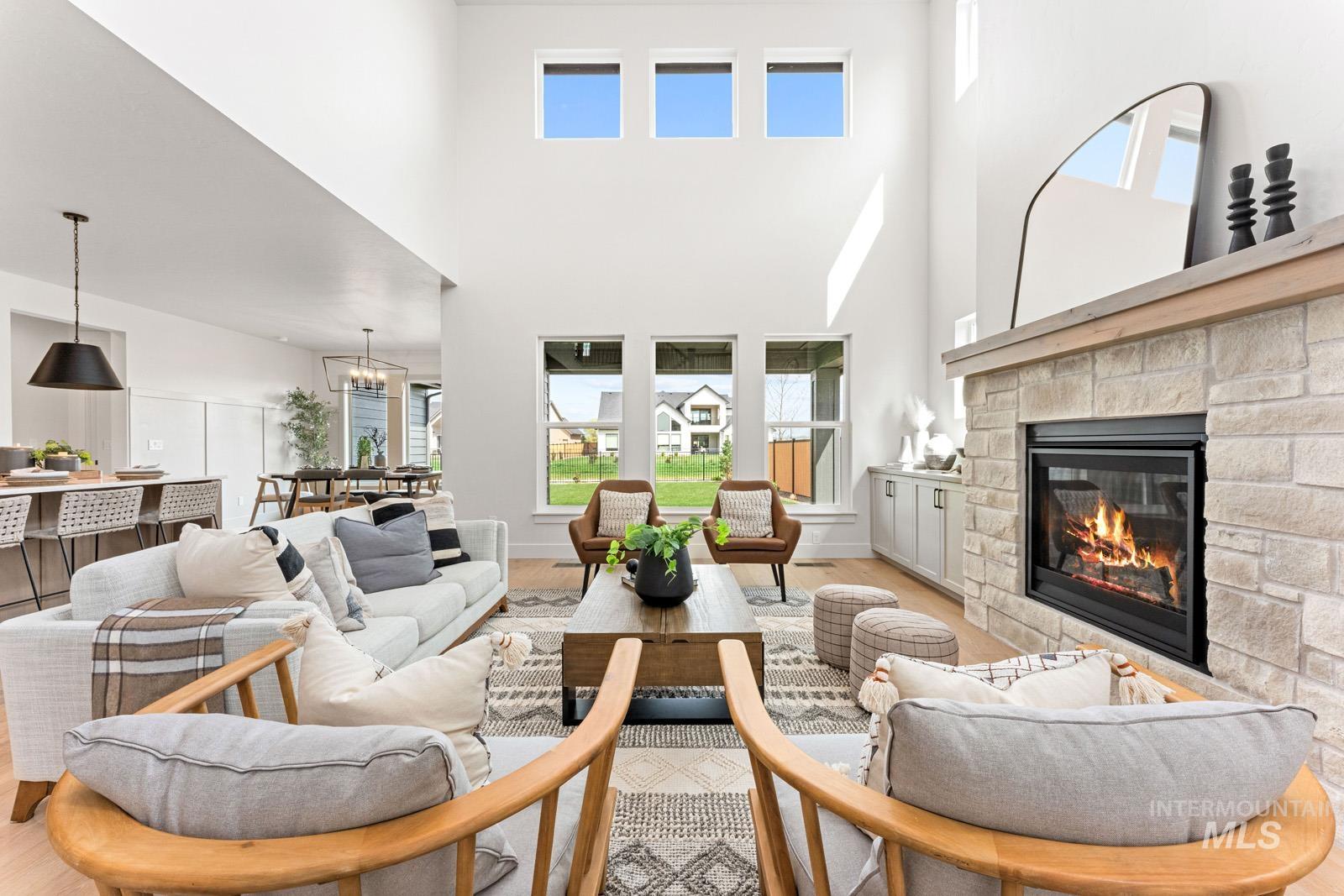 6792 Saddle Bred Way Star, ID 83669 - Photo 3 of 50 Living room with light wood-style flooring, a fireplace, hanging lights, and a high ceiling