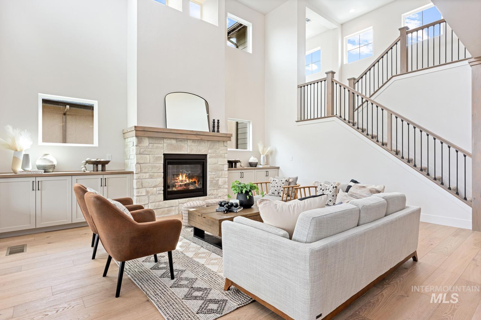 6792 Saddle Bred Way Star, ID 83669 - Photo 6 of 50 Living room featuring light wood-style flooring, a stone fireplace, and a high ceiling