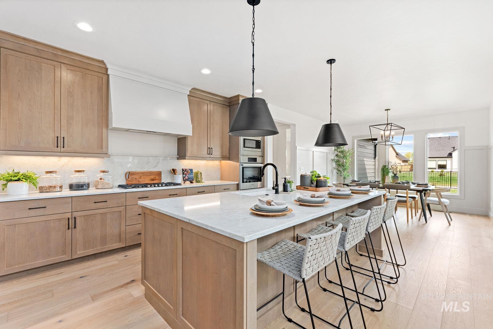 6792 Saddle Bred Way Star, ID 83669 - Photo 7 of 50 Kitchen featuring an island with sink, a kitchen bar, light stone countertops, tasteful backsplash, and light wood-style floors