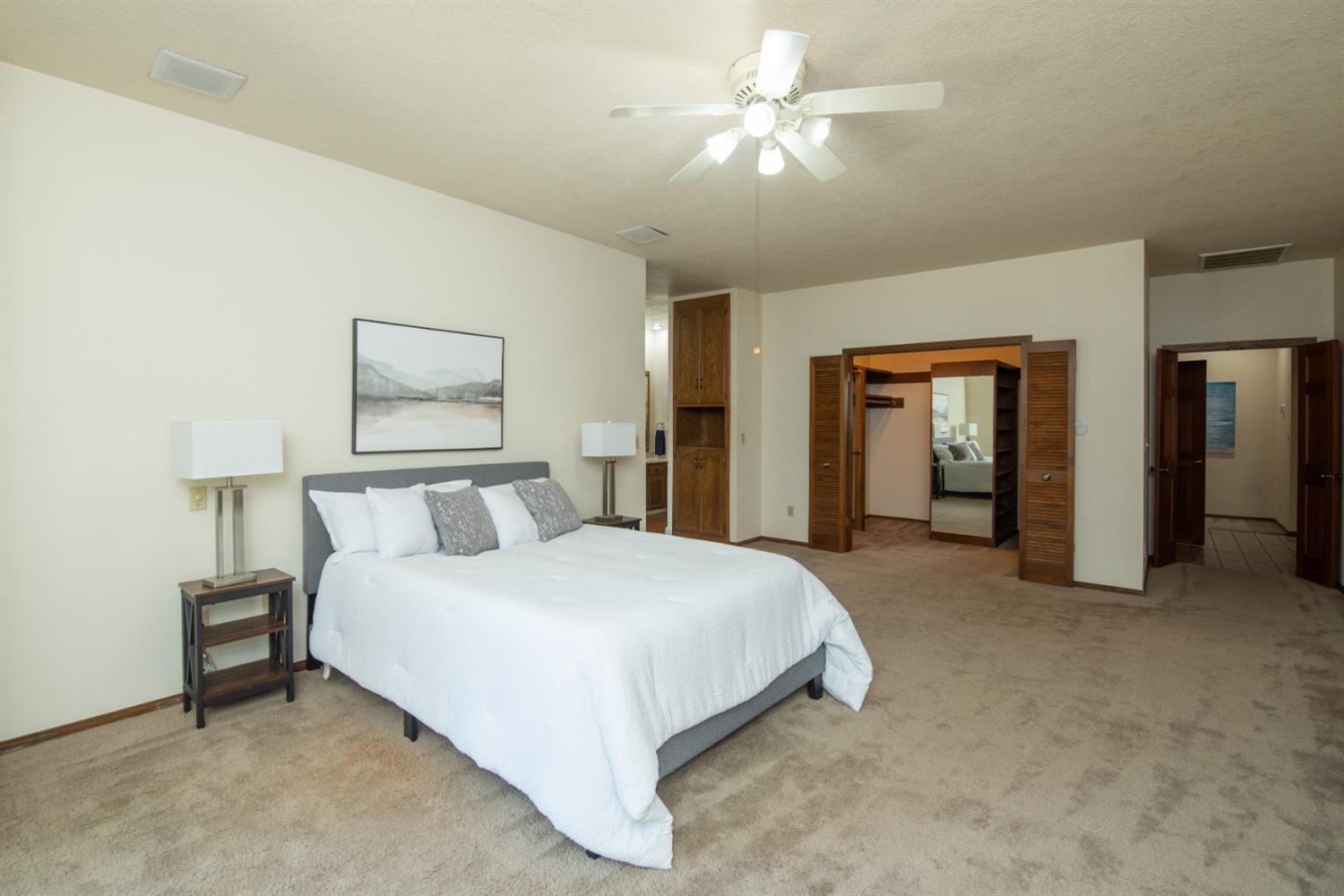925 Scenic Court Modesto, CA 95355 - Photo 34 of 62 a spacious bedroom with a bed and a chandelier