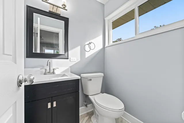 a bathroom with a granite countertop toilet sink and mirror