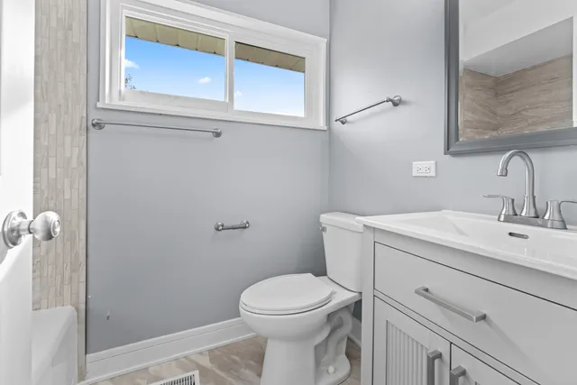 a bathroom with a toilet sink vanity and mirror