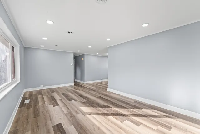 a view of empty room with wooden floor and fan
