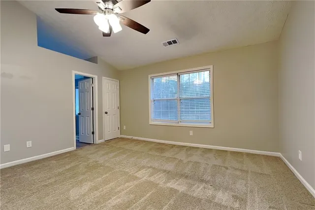 a view of an empty room with window and chandelier fan