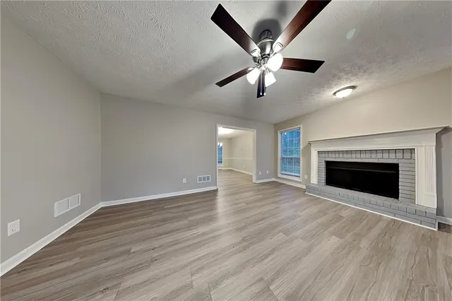 a view of an empty room with wooden floor and a fireplace