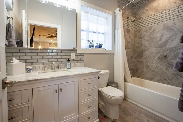 a bathroom with a granite countertop sink toilet a large mirror a bathtub and shower