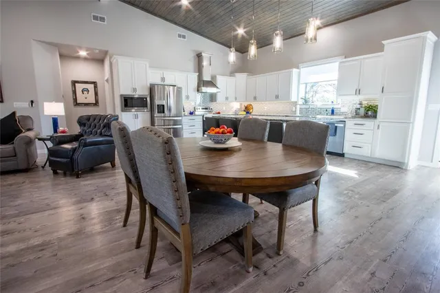a kitchen with stainless steel appliances kitchen island granite countertop a dining table chairs and view living room