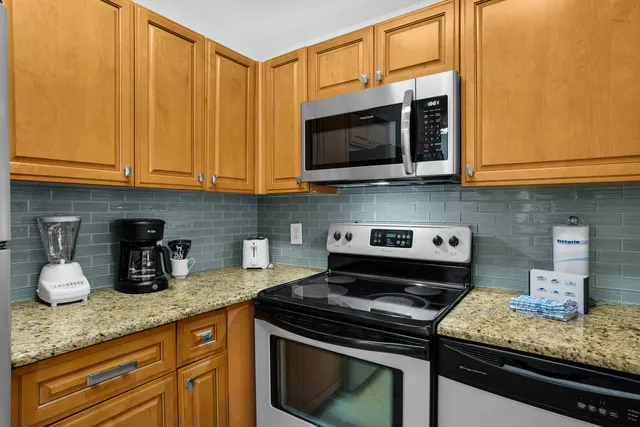 a kitchen with stainless steel appliances granite countertop a refrigerator and a stove top oven