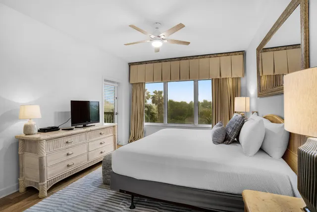 a bedroom with a large bed and a flat tv screen on dresser