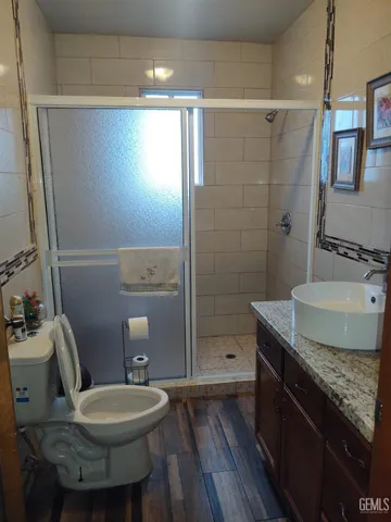 a bathroom with a granite countertop sink a toilet a mirror and shower