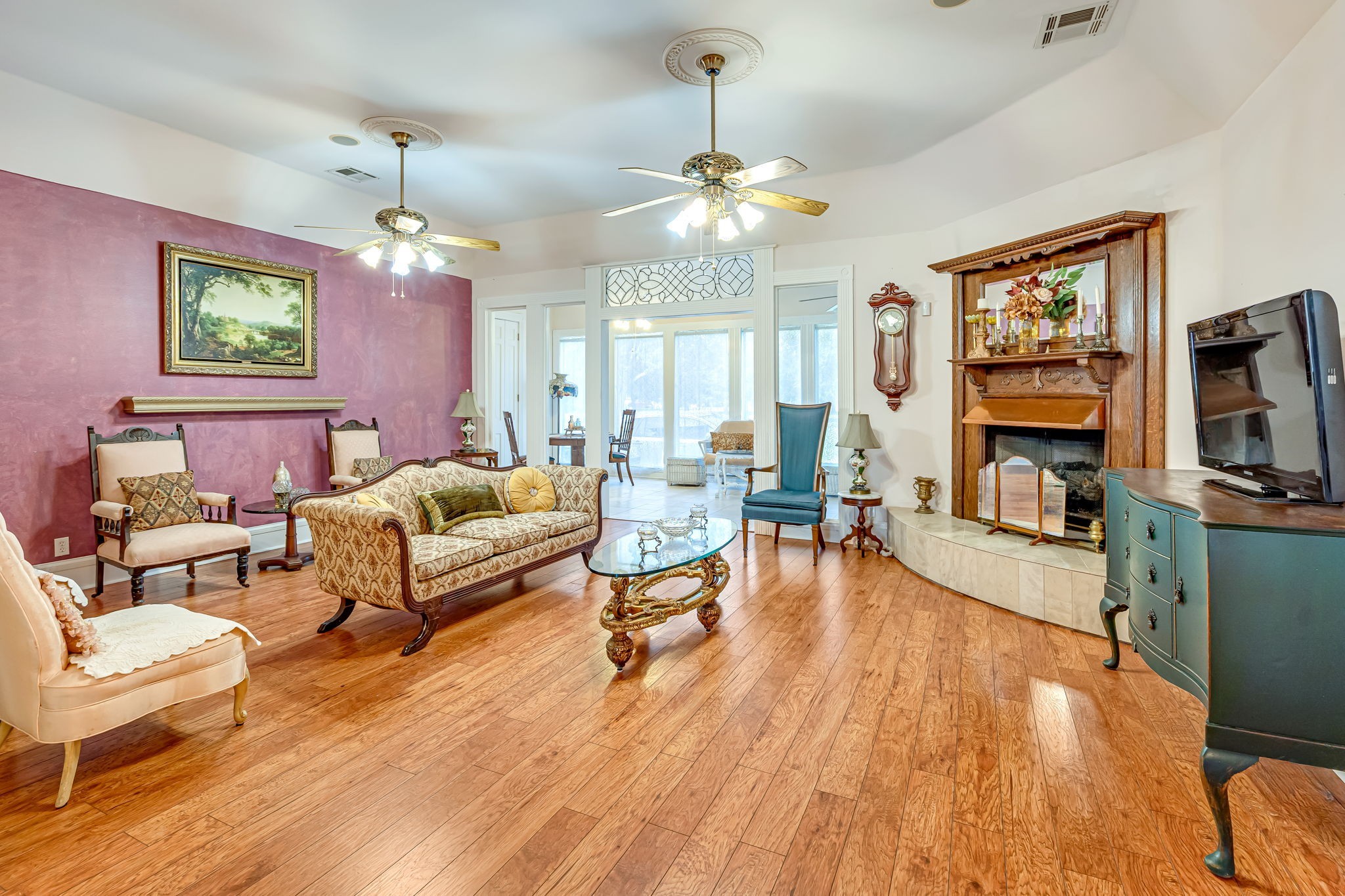 4028 Crosby Cedar Bayou Road Baytown, TX 77521 - Photo 18 of 35 Grand living room—high ceilings with dual fans, hardwoods, and a decorative fireplace; French doors open to a sunny sitting/sun room.