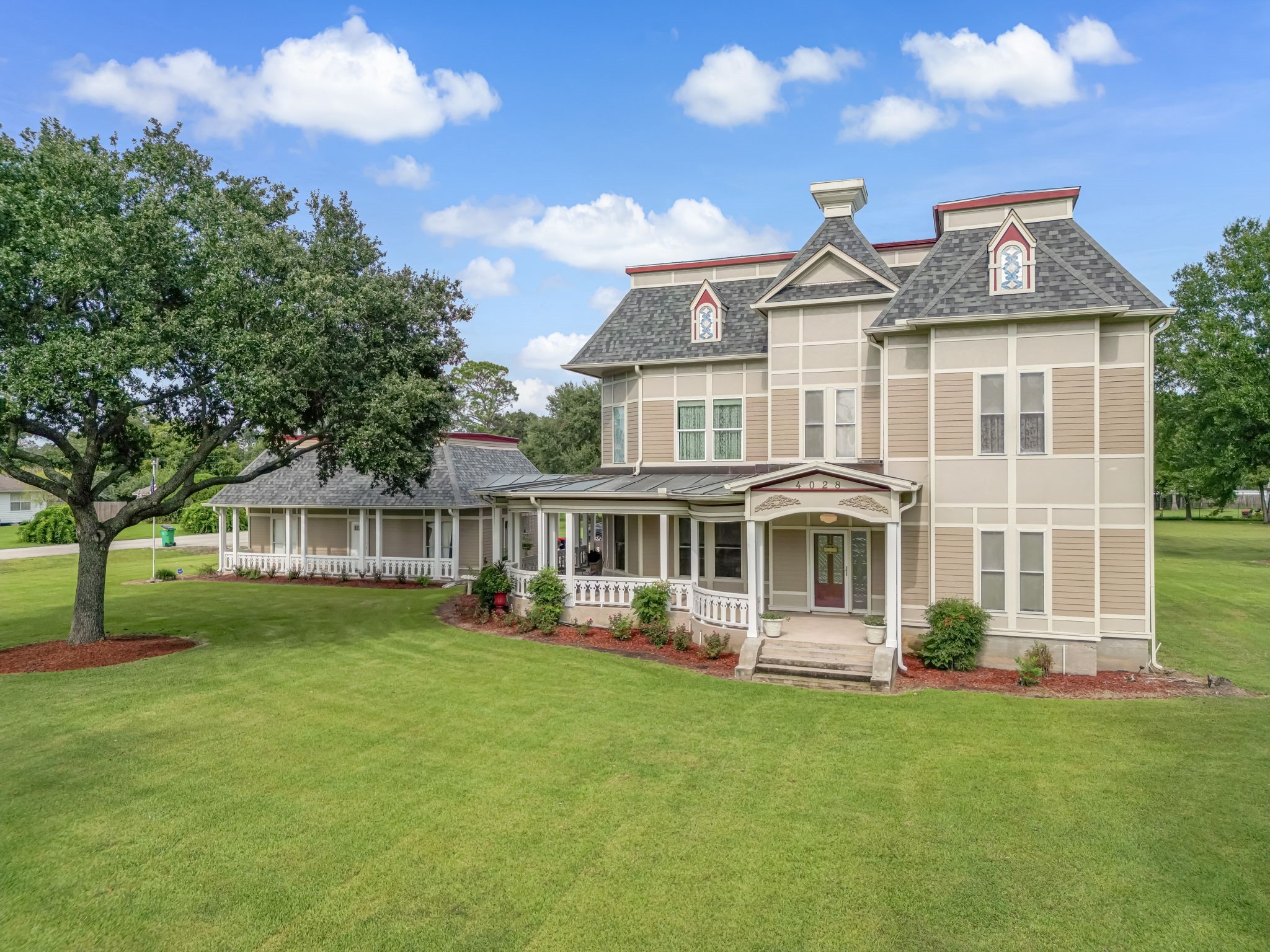 4028 Crosby Cedar Bayou Road Baytown, TX 77521 - Photo 2 of 35 This angle highlights the home’s timeless Victorian details—ornate gables and dormers, a welcoming wraparound porch, and graceful trim work—flowing into an extended side wing for added living space. Wide, manicured lawns and mature trees complete the storybook setting.