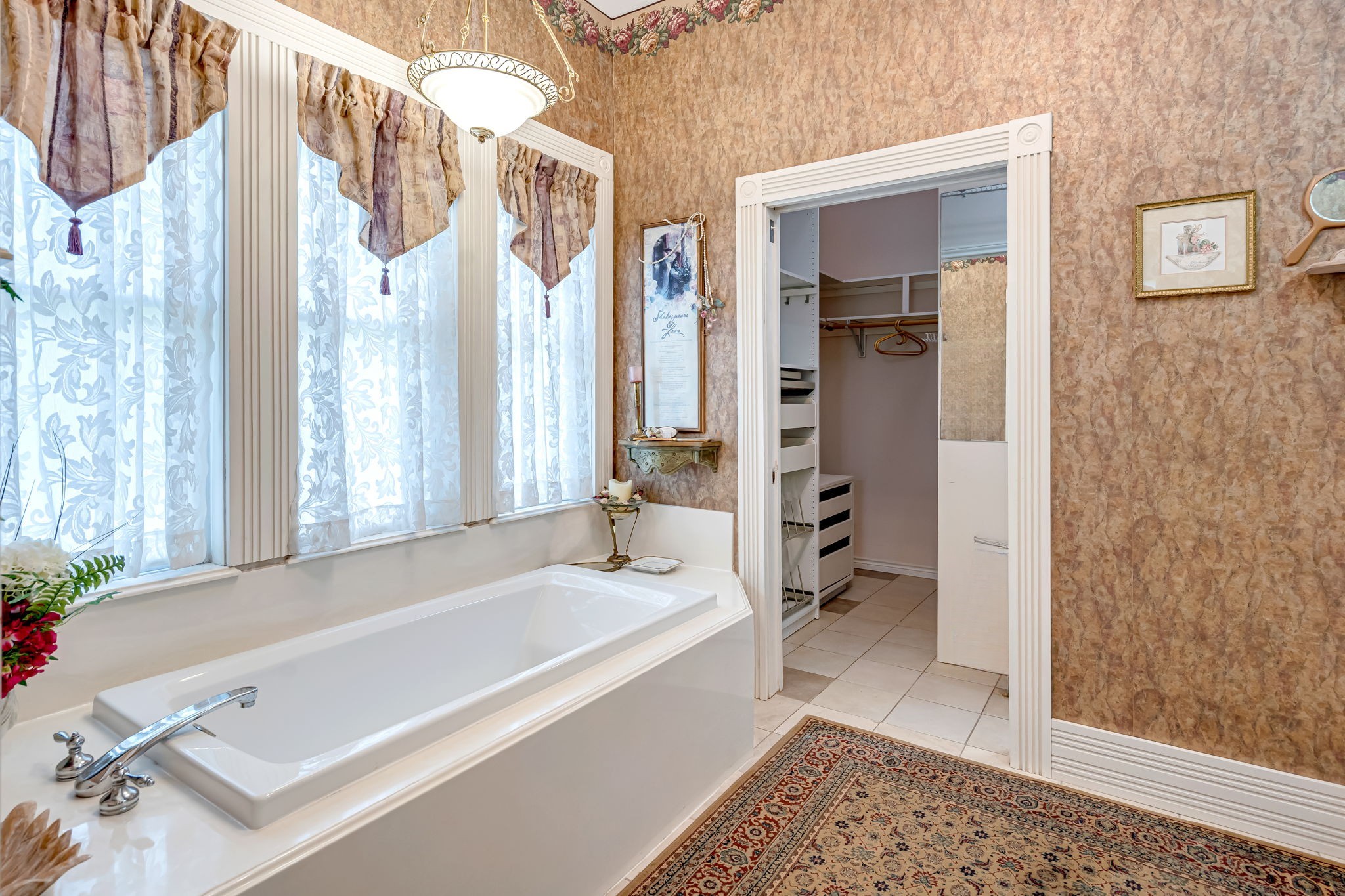 4028 Crosby Cedar Bayou Road Baytown, TX 77521 - Photo 24 of 35 A serene corner of the primary suite: a deep soaking tub sits beneath tall, lace-dressed windows, while a cased opening leads to the adjacent walk-in closet. For convenience and privacy, the bath also features a separate step-in shower and private toilet area—an ideal layout for daily routines.