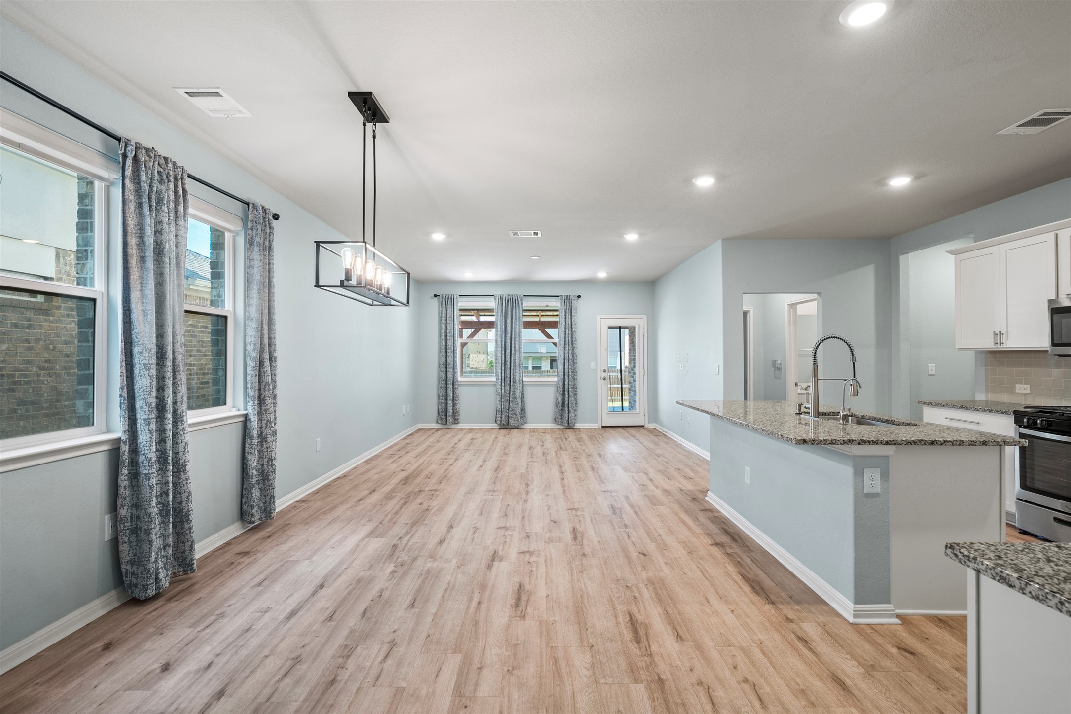 120 Ellinger Road Georgetown, TX 78626 - Photo 13 of 28 Spacious open-concept interior featuring wood-finish flooring, recessed lighting, and a modern linear chandelier