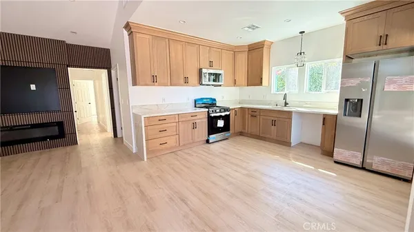 a large kitchen with stainless steel appliances granite countertop a refrigerator a stove and a wooden floors