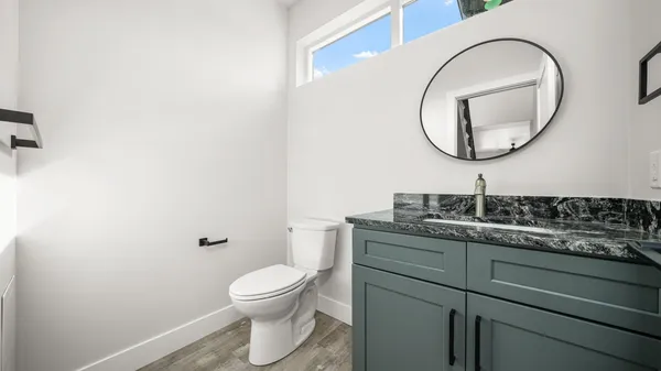 a bathroom with a granite countertop toilet a sink and a mirror