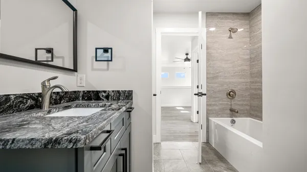 a bathroom with a granite countertop tub sink and mirror