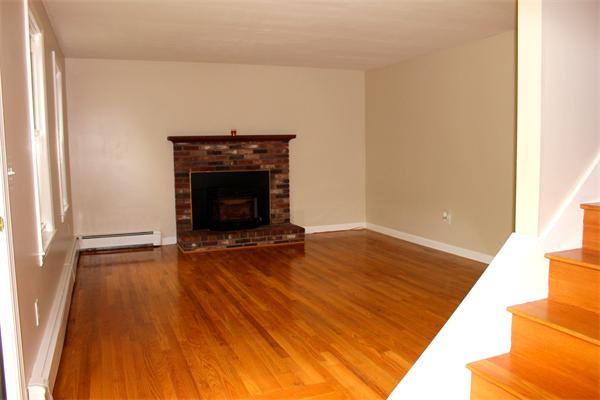 689 Walnut Plain Road Rochester, MA 02770 - Photo 5 of 22 a view of an empty room with wooden floor fireplace and a window