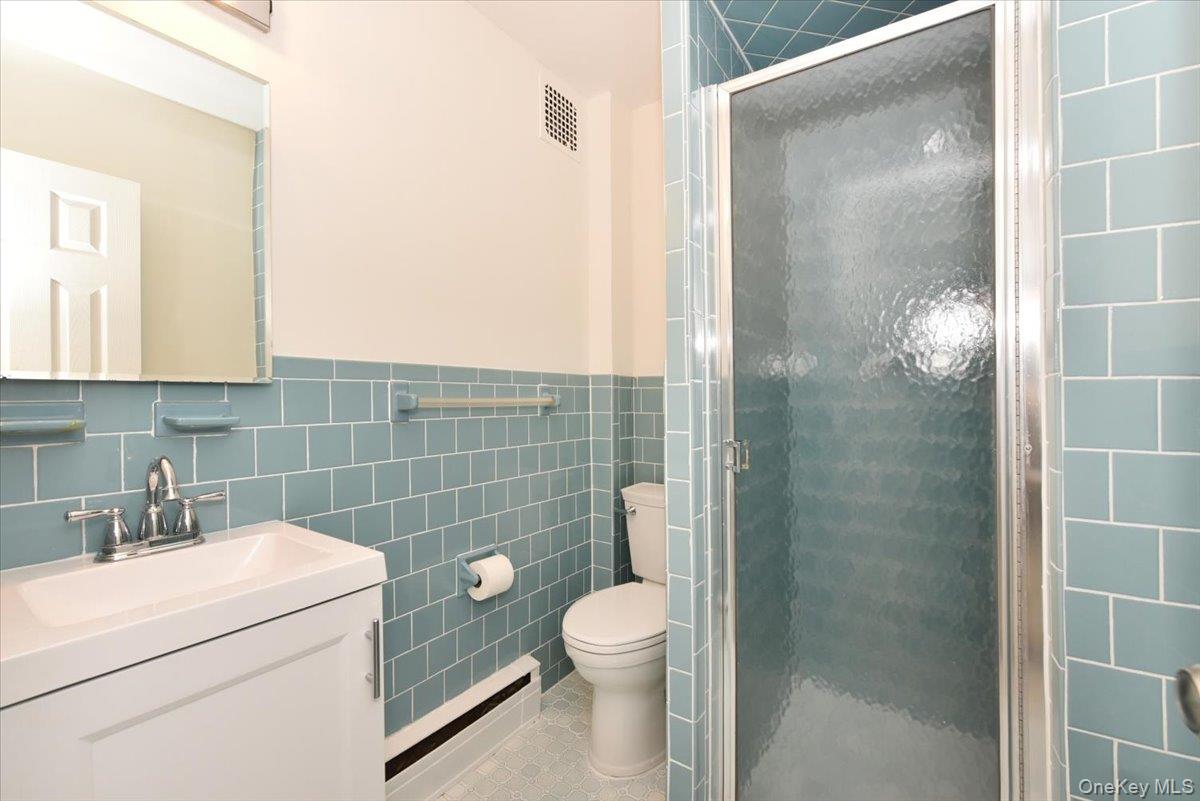 195 South Middle Neck Road, Unit 2L Great Neck, NY 11021 - Photo 21 of 36 a bathroom with a granite countertop toilet a sink and a mirror