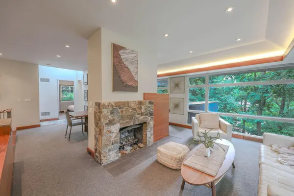 a living room with furniture a fireplace and a floor to ceiling window