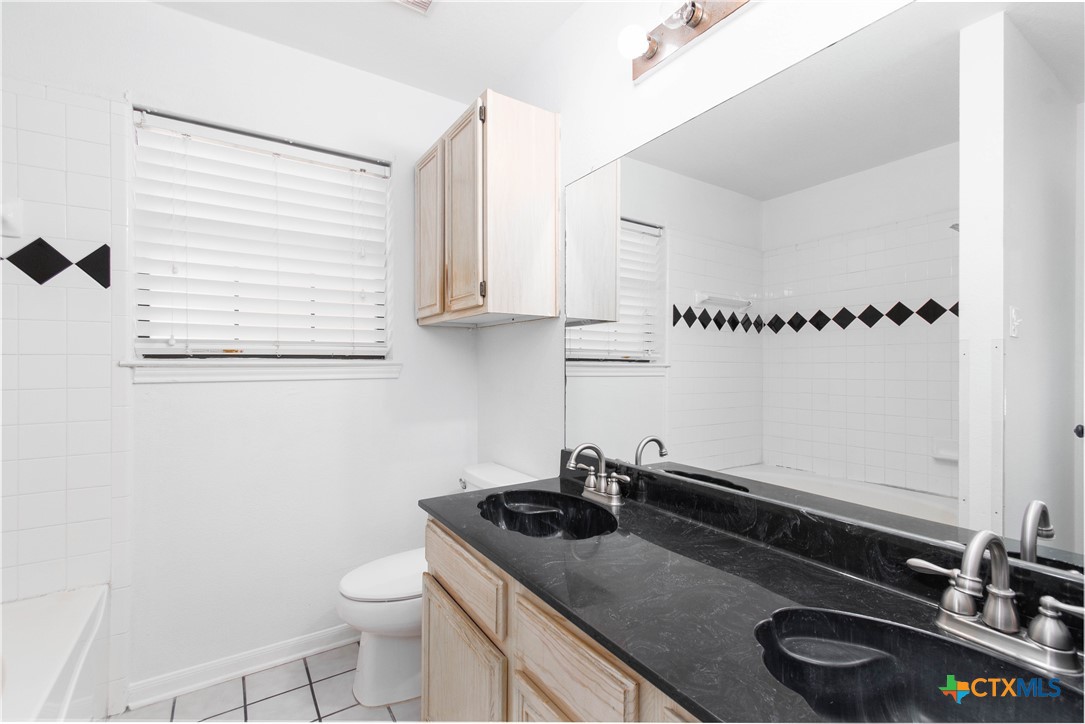 5420 Williams Drive Temple, TX 76502 - Photo 11 of 24 a bathroom with a granite countertop sink a toilet and a mirror
