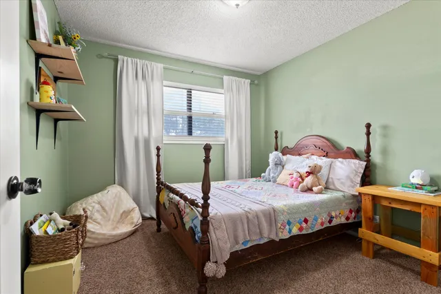 a bedroom with a bed table flowerpot and window
