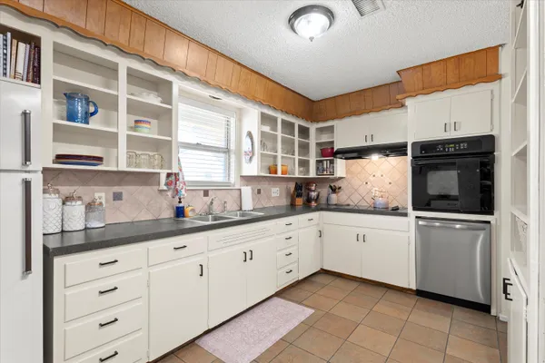 a kitchen with granite countertop white cabinets stainless steel appliances a sink and a counter top space