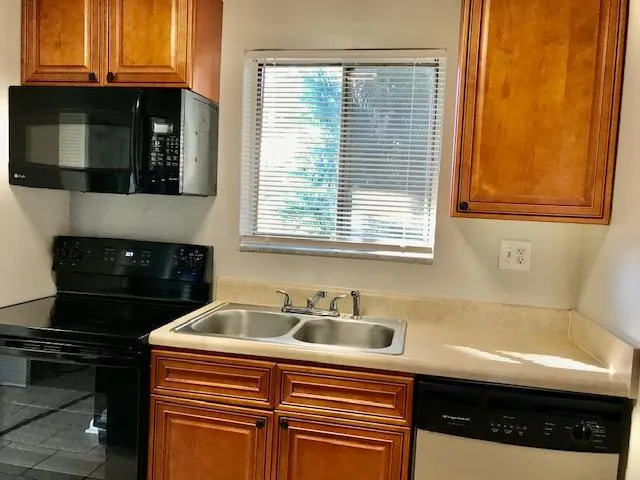 a kitchen with stainless steel appliances granite countertop a refrigerator a stove and a sink